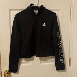 Cropped black pullover with white Adidas lettering on the sleeve.